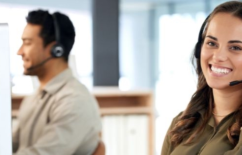 Smiling customer service representative wearing a headset in an office setting 705291934